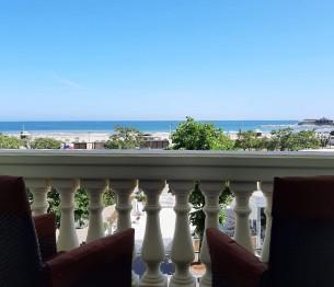 Vista mare da un balcone con sedie e cielo sereno.