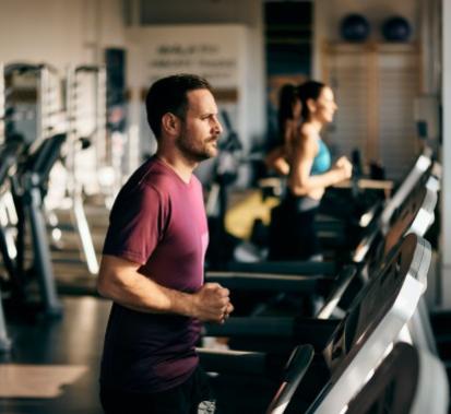 Persone che corrono su tapis roulant in palestra, concentrati sull'allenamento.