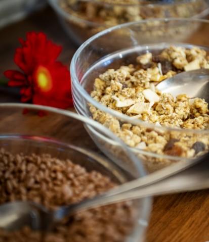 Ciotole di cereali con granola e cioccolato, decorazione floreale rossa sullo sfondo.