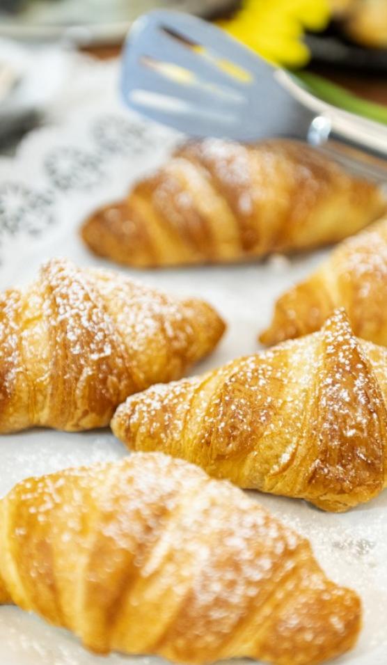 Croissant dorati spolverati di zucchero a velo su un vassoio.