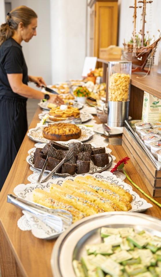 Buffet con dolci e cereali, una persona serve cibo su un piatto.