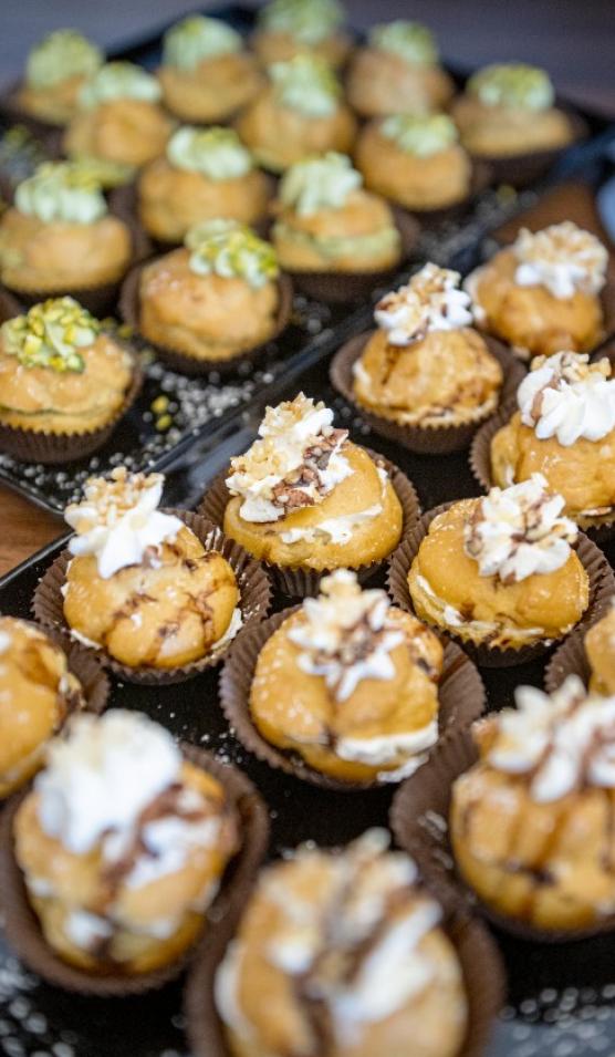 Dolcetti decorati con crema e noci, disposti su vassoi per un buffet.