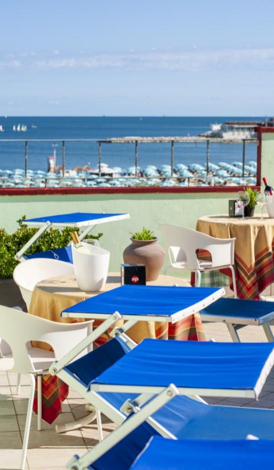 Terrazza con lettini blu e vista mare, perfetta per rilassarsi al sole.