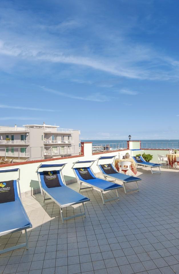 Terrazza con lettini blu e vista mare, perfetta per il relax estivo.