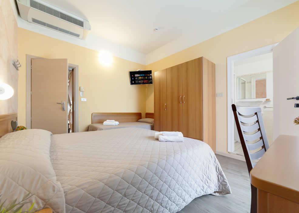 Camera d'albergo accogliente con letto matrimoniale, armadio e TV a parete.