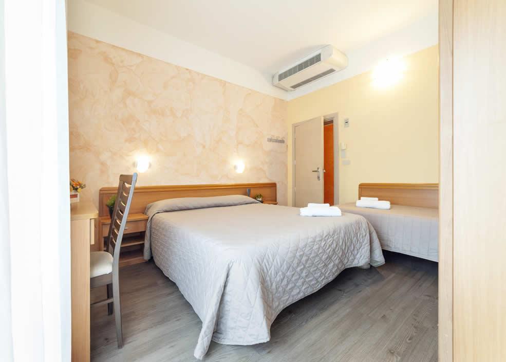 Camera d'albergo luminosa con letto matrimoniale, aria condizionata e decorazioni semplici.